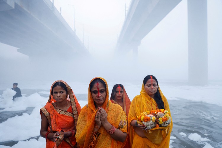 Potret Warga India Gelar Ritual di Sungai Penuh Limbah Beracun Hindu devotees worship the Sun god as they stand amidst the foam covering the polluted Yamuna river during the Hindu religious festival of Chhath Puja on a smoggy morning in New Delhi, India, November 20, 2023. REUTERS/Anushree Fadnavis TPX IMAGES OF THE DAY