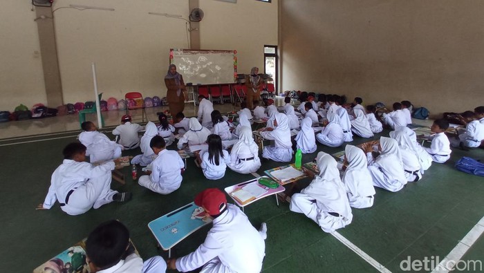 Siswa kelas 1 dan kelas 2 SDN Kedungdawa, Kabupaten Cirebon belajar di lapangan badminton akibat atap ruang kelas ambruk/(Foto: Ony Syahroni/detikJabar)
