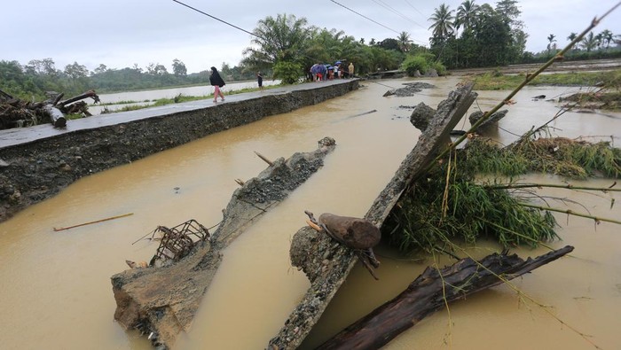 Jalan rusak diterjang banjir di Aceh Barat Warga berada di dekat jalan yang rusak akibat diterjang banjir di Desa Seumantok, Pante Ceureumen, Aceh Barat, Aceh, Selasa (21/11/2023). Banjir yang disebabkan tingginya intensitas hujan dan meluapnya Sungai krueng Meureubo sejak Senin (20/11/2023) mengakibatkan badan jalan sepanjang 110 meter diterjang arus banjir dan dapat membahayakan keselamatan pengguna jalan terutama saat malam hari. ANTARA FOTO/Syifa Yulinnas/rwa.