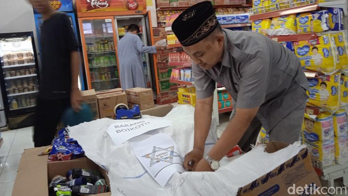 Manajer HK Mart Ponpes Husnul Khotimah Kuningan Hendrik Susila memasang tulisan Barang Boikot di atas tumpukan produk berafiliasi Israel .