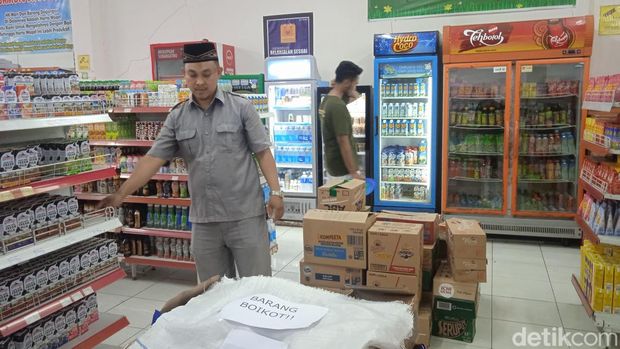 Manajer HK Mart Ponpes Husnul Khotimah Kuningan Hendrik Susila memasang tulisan 