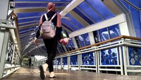 Warga melintas di Jembatan Penyeberangan Orang (JPO) Klender, Jakarta, Selasa (21/11/2023).