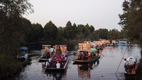 Little Amal, boneka setinggi 12 kaki yang menggambarkan seorang pengungsi Suriah berusia 10 tahun, mengendarai perahu di kanal air di Xochimilco di pinggiran Mexico City, Meksiko, Minggu (19/11/2023).