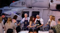 Biden menyajikan porsi kentang tumbuk dan Jill Biden menyendok casserole ubi jalar saat pengunjung lewat di depan mereka.  