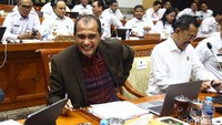 Tampak Eddy mengenakan jas coklat dan sempat menebar senyum ke awak media.  