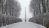 Seorang wanita berjalan di taman yang tertutup salju saat hujan salju pertama di Kyiv, Ukraina. 