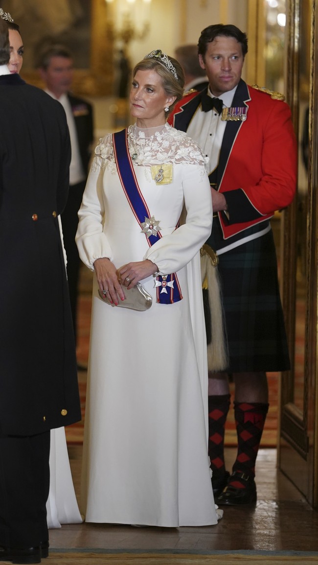 Sophie, Duchess of Edinburgh, anggun dalam balutan gaun putih. Gayanya dipermanis dengan panel bordiran yang menghiasi area bahu. Tidak ketinggalan sebuah tiara menghiasi kepalanya. (Foto: AP/Yui Mok)