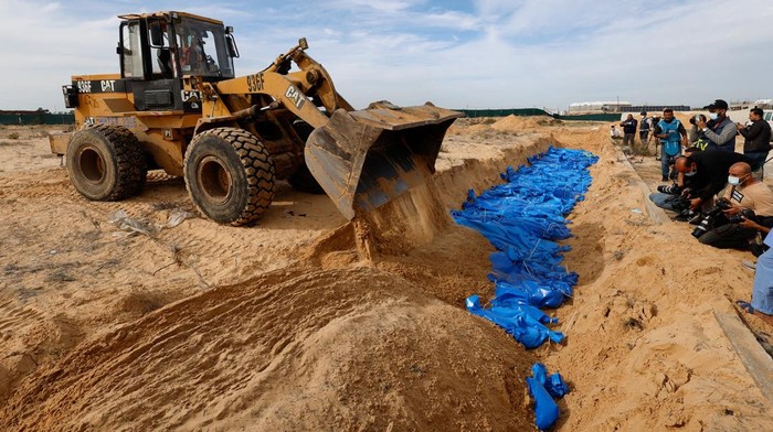 The bodies of Palestinians killed in Israeli strikes and fire are buried in a mass grave, after they were transported from Al Shifa hospital in Gaza City for burial, in Khan Younis in the southern Gaza Strip November 22, 2023. REUTERS/Mohammed Salem