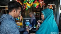 Achieng melakukan sosialisasi penggunaan aplikasi BRImo dan pembayaran QRIS kepada warga.