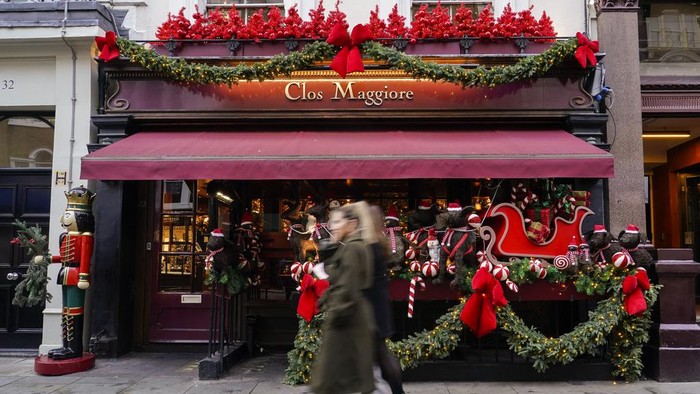 Christmas decorations are seen outside a restaurant in the area of Covent Garden as people walk past, in London, Tuesday, Nov. 21, 2023.(AP Photo/Alberto Pezzali)