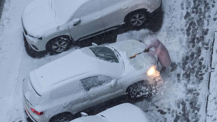 A woman cleans a car covered in snow during a first snowfall, amid Russia's attack on Ukraine, in Kyiv, Ukraine November 22, 2023. REUTERS/Gleb Garanich