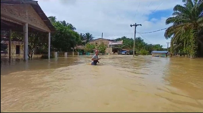 Warga melintasi banjir di Dusun I Desa Piasa Ulu Kecamatan Tinggi Raja Kabupaten Asahan. (Istimewa)