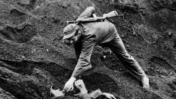 Seorang marinir AS memberikan rokok kepada tentara Jepang yang terluka, terkubur di pasir pada pertempuran Iwo Jima pada tahun 1945. Foto: Boredpanda