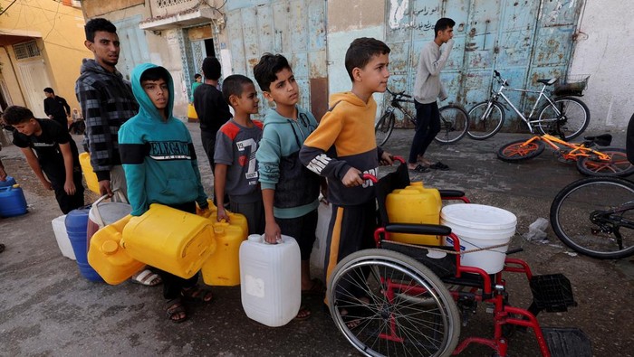 A Palestinian child looks up while waiting in a line with containers to collect water, amid drinking water shortages, in Rafah in the southern Gaza Strip, November 23, 2023. REUTERS/Ibraheem Abu Mustafa