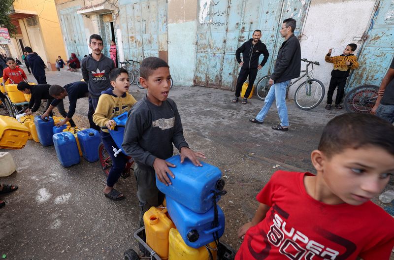 A Palestinian child looks up while waiting in a line with containers to collect water, amid drinking water shortages, in Rafah in the southern Gaza Strip, November 23, 2023. REUTERS/Ibraheem Abu Mustafa