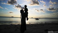 Seorang warga bersama anaknya bermain di pasir putih pantai Tanah Beru.  