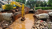 Sebuah ekskavator dioperasikan memperbaiki jalan.  