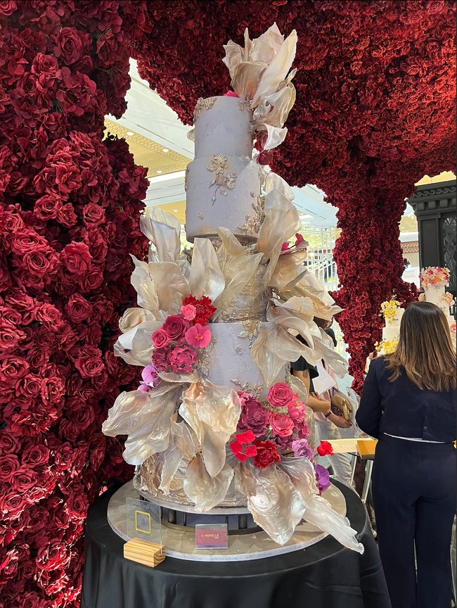 Terdiri dari beberapa tingkat, kue pernikahan yang didominasi warna soft gold dengan sentuhan ornamen bunga berwarna merah muda bisa menjadi pertimbangan. Perpaduan warna tersebut membuat kue terlihat elegan namun tetap tidak berlebihan. Foto: Wolipop/Vina Oktiani