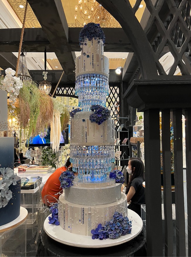 Didominasi warna putih dan biru, desain kue pernikahan yang satu ini terlihat elegan dan mewah dengan tambahan ornamen kristal yang tergantung di bagian bawah beberapa layer kue. Masing-masing layer kuenya pun tampak memiliki cukup banyak ornamen yang membuat kue terlihat semakin cantik. Foto: Wolipop/Vina Oktiani