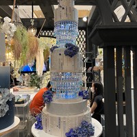Didominasi warna putih dan biru, desain kue pernikahan yang satu ini terlihat elegan dan mewah dengan tambahan ornamen kristal yang tergantung di bagian bawah beberapa layer kue. Masing-masing layer kuenya pun tampak memiliki cukup banyak ornamen yang membuat kue terlihat semakin cantik. Foto: Wolipop/Vina Oktiani