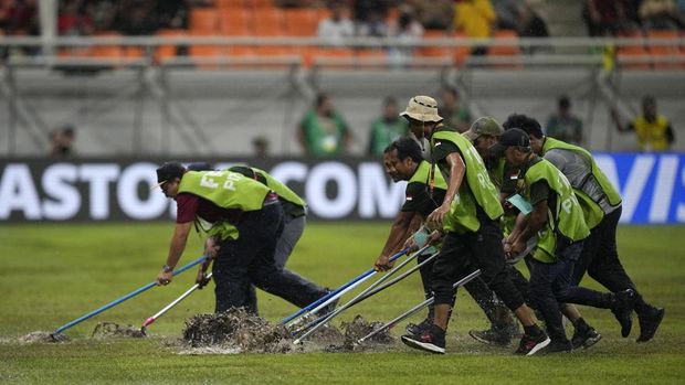 Para pekerja mencoba mengalirkan air dari lapangan setelah hujan lebat menjelang pertandingan sepak bola perempat final Piala Dunia U-17 FIFA antara Brasil dan Argentina di Jakarta Internasional Stadum pada Jumat, (24/11/2023). (AP Photo/Achmad Ibrahim)