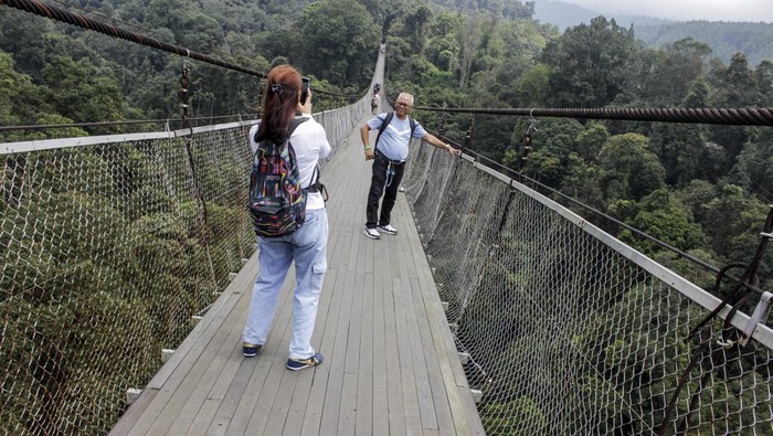 Pengunjung melintas di jembatan gantung Lembah Purba di kawasan wisata Situgunung, Kadudampit, Kabupaten Sukabumi, Jawa Barat, Minggu (26/11/2023). Kementerian Pariwisata dan Ekonomi Kreatif menargetkan kunjungan wisatawan mancanegara naik menjadi 12-14 juta pada 2024 dibandingkan target 2023 sebanyak 8,5 juta kunjungan dan target pergerakan wisatawan nusantara kisaran 1,2 miliar - 1,4 miliar pada 2024. ANTARA FOTO/Henry Purba/agr/nym.