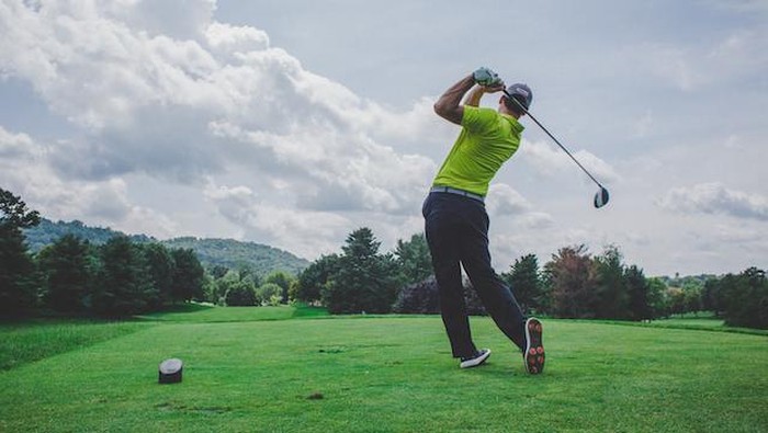 Bermain golf di lapangan golf.