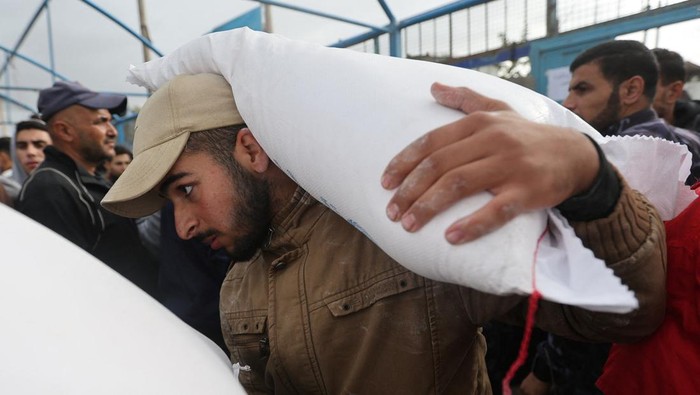 A Palestinian woman presents her ration card to receive flour bags distributed by the United Nations Relief and Works Agency (UNRWA) during a temporary truce between Hamas and Israel, in Khan Younis in the southern Gaza Strip November 27, 2023. REUTERS/Ibraheem Abu Mustafa