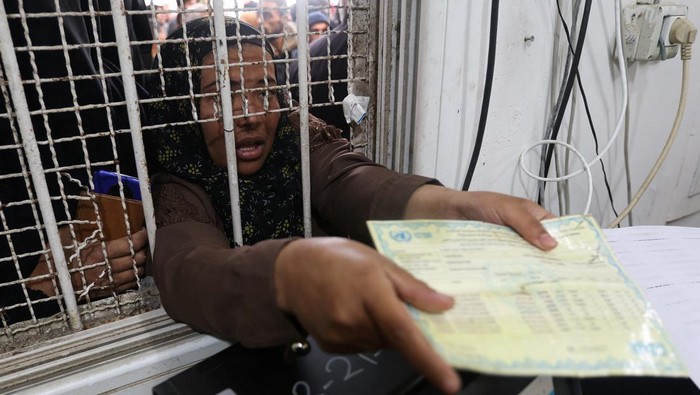 A Palestinian woman presents her ration card to receive flour bags distributed by the United Nations Relief and Works Agency (UNRWA) during a temporary truce between Hamas and Israel, in Khan Younis in the southern Gaza Strip November 27, 2023. REUTERS/Ibraheem Abu Mustafa