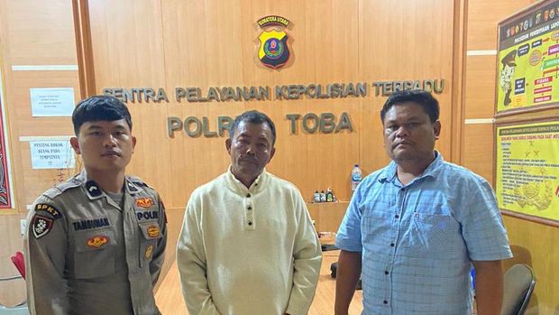 Lukman Dolok Saribu (57) diapit dua polisi di Polres Toba. (Foto: Dok. Polda Sumut)