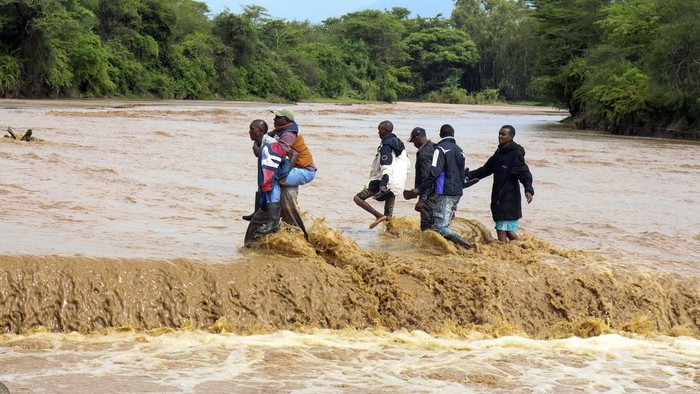 Potret Warga Kenya Nekat Seberangi Sungai yang Meluap People cross through a flooded Muuoni River, where 8 people are said to have drowned overnight while crossing the river at Mukaa area, Makueni county, Eastern Kenya, Friday Nov. 24, 2023. Flood-related death toll is going higher everyday as heavy rains continue to pound across East Africa. (AP Photo )