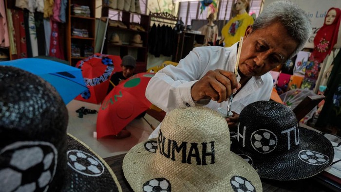 Perajin kain lukis Nasrafa menyelesaikan pembuatan payung lukis bermotif bola di Sentra IKM (Industri Kecil Menengah) Semanggi Harmoni Solo, Jawa Tengah, Senin (27/11/2023). Produk payung lukis dan topi lukis tersebut dijual untuk souvernir menyambut laga semifinal dan final FIFA U-17 World Cup 2023 di Stadion Manahan Solo. ANTARAFOTO/Maulana Surya/rwa.