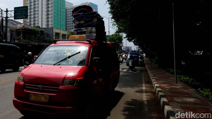 Sebuah angkot mengangkut kasur bertumpuk-tumpuk di Ciracas, Jakarta Timur. Padahal, mengangkut barang di atap mobil secara berlebih tidak disarankan.