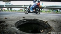 Pengendara melintas di samping lubang yang ada di Jalan Raya Kalimalang, Kota Bekasi, Selasa (28/11/2023).  