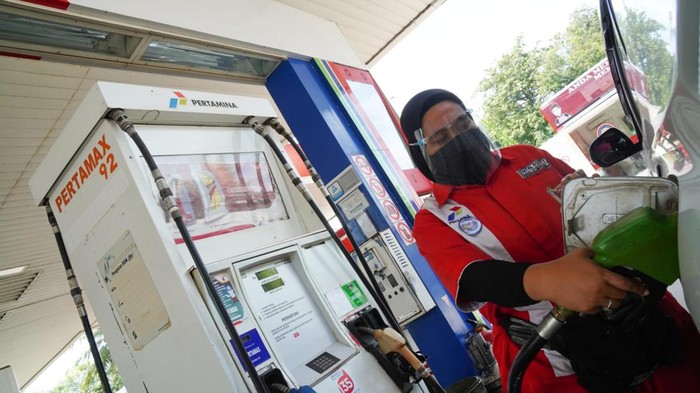 Petugas SPBU sedang mengisi BBM ke mobil pelanggan.