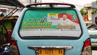 Tidak hanya dipasang di pinggir jalan, alat peraga kampanye itu juga terpampang di kaca angkutan kota.  