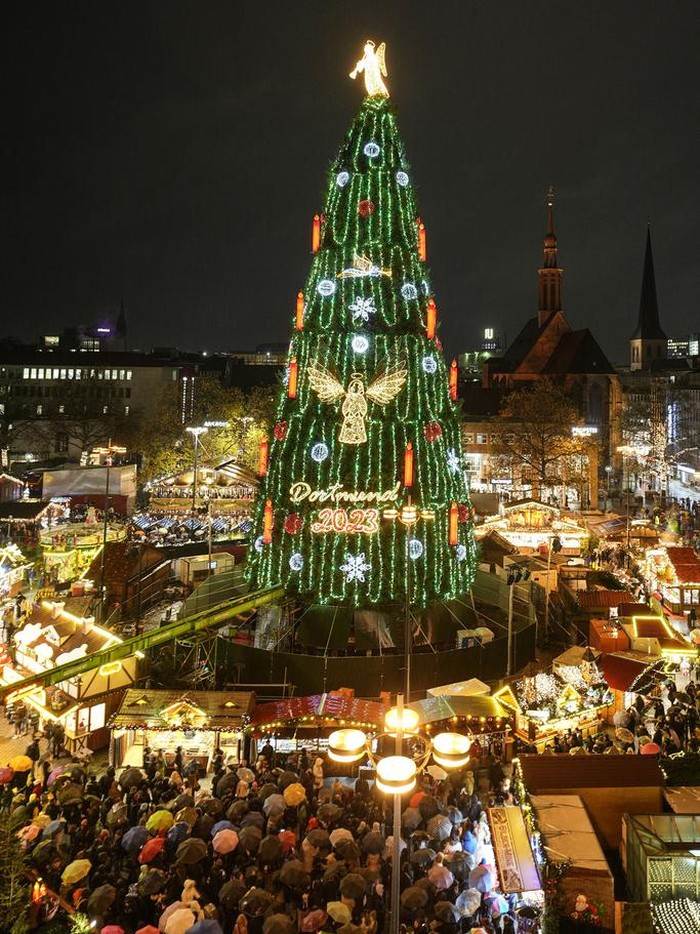 The traditional 45 meter high Christmas tree is illuminated at the Christmas market in Dortmund, Germany, Monday, Nov. 27, 2023. According to the city of Dortmund, it is the world's largest Christmas tree, made of more than 1000 red spruces and illuminated by 48,000 lamps. (AP Photo/Martin Meissner)