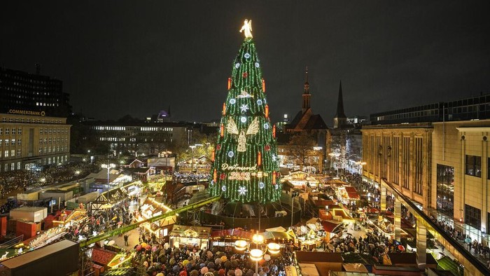 The traditional 45 meter high Christmas tree is illuminated at the Christmas market in Dortmund, Germany, Monday, Nov. 27, 2023. According to the city of Dortmund, it is the world's largest Christmas tree, made of more than 1000 red spruces and illuminated by 48,000 lamps. (AP Photo/Martin Meissner)