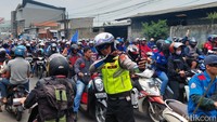 Pihak kepolisian berupaya mengatur kemacetan dengan menggeser sedikit kendaraan roda dua para buruh agar bisa memberi sedikit ruang bagi kendaraan lain supaya arus lalu lintas tetap bisa mengalir.