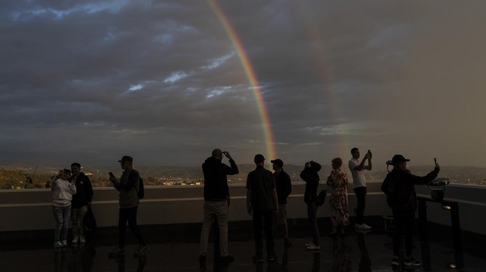 Visitors take selfies with a double rainbow at the Griffith Observatory in Los Angeles, Wednesday, Nov. 29, 2023. (AP Photo/Jae C. Hong)