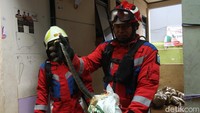Warga dan petugas menemukan seekor ular saat bersih-bersih sisa banjir.