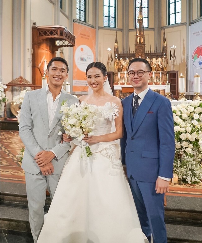 Jonatan Christie tampak mengenakan kemeja putih dipadu setelan jas abu-abu rancangan Wong Hang Tailor. Korsase mawar putih disematkan di dada sebagai pemanis. Foto: Instagram/@jonathanwongso @haruuuu_chan