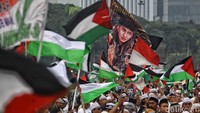Massa membawa bendera dan spanduk untuk mendukung perjuangan Palestina melawan Israel.
