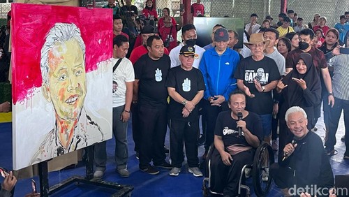Calon presiden (capres) nomor urut 3 Ganjar Pranowo dihadiahi lukisan bergambar wajahnya oleh seniman penyandang disabilitas asal Lombok bernama Nyoman Mantra, Minggu (3/12/2023). (Helmy Akbar/detikBali)
