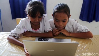 Dua orang siswa tampak serius belajar menggunakan laptop yang terkoneksi dengan internet. 