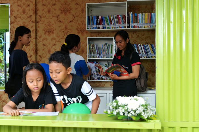Pengunjung membaca buku koleksi Perpustakaan Semi-Kontainer di kawasan Taman Janggan, Denpasar, Bali, Minggu (3/12/2023). Perpustakaan yang memanfaatkan bangunan kontainer itu dibangun di titik keramaian untuk meningkatkan minat baca warga sekaligus sebagai upaya inovasi layanan untuk mendekatkan perpustakaan ke masyarakat. ANTARA FOTO/Fikri Yusuf/rwa.