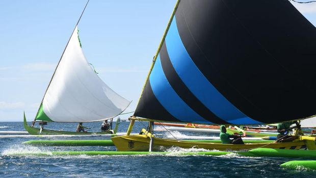 Dozens of boats with fluttering sails sail the Bali Strait. Perahu layar tradisional tersebut berpacu dengan ombak laut Bali.