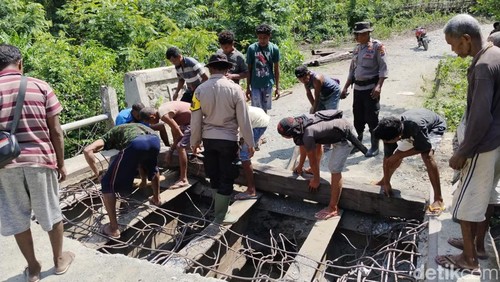 Sejumlah warga dan polisi swadaya memperbaiki Jembatan Poti di Desa Afoan, Kecamatan Amfoang Utara, Kabupaten Kupang, NTT.