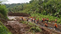 Petugas menyingkirkan material longsor yang menutup jalur rel kereta api di lintas stasiun Karanggandul-Karangsari. Perjalanan kereta api yang melintas di DAOP 5 Purwokerto, dialihkan memutar melalui Bandung atau Semarang.