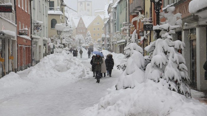 People walk on a snow covered street in the old town of Füssen, Germany, Saturday, Dec. 2, 2023. (Christian Wiediger/dpa via AP)